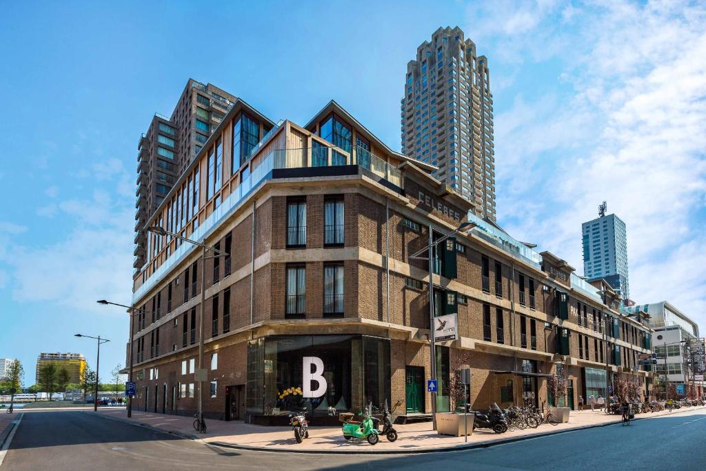 Room Mate Bruno on Wilhelminakade, a converted brick warehouse with a large letter B at street level and Rotterdam towers behind