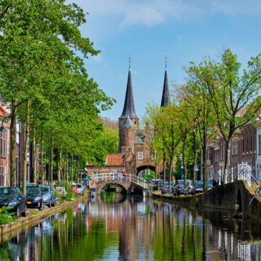Picturesque canal in Delft city centre with the historic Oostpoort gate, Netherlands