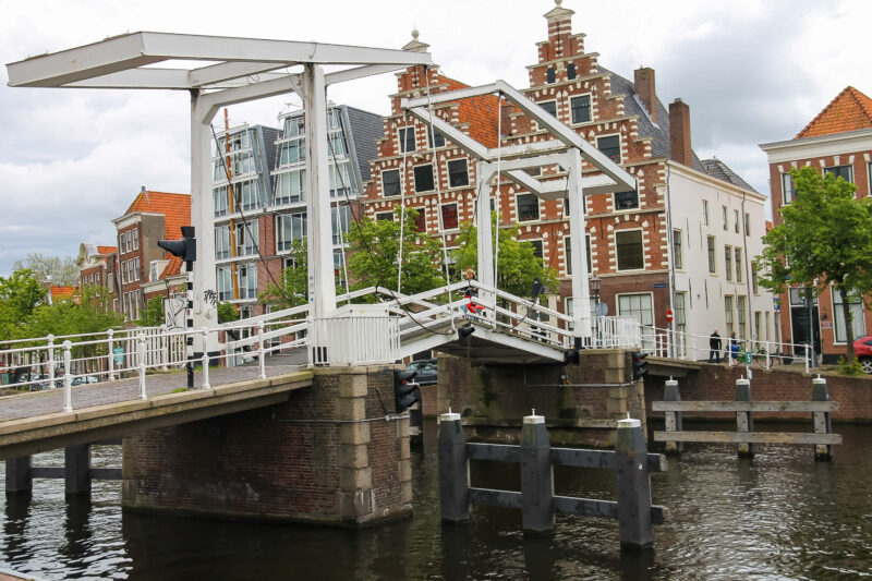 Traditional white drawbridge over the Spaarne river in Haarlem with historic Dutch step-gable merchant houses in the background