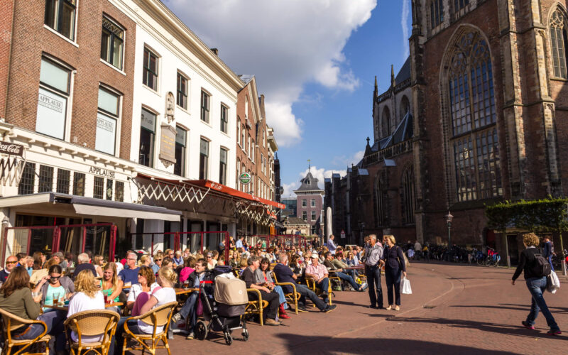 Busy terrace café on the Grote Markt in Haarlem with the Sint-Bavokerk in the background — dining option for cruise passengers from IJmuiden