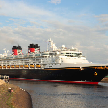 Disney Magic cruise ship sailing through the North Sea Canal at IJmuiden, Netherlands, with the canal dike in the foreground