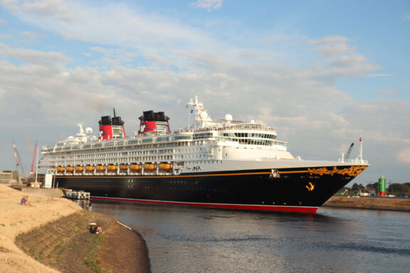 Disney Magic cruise ship sailing through the North Sea Canal at IJmuiden, Netherlands, with the canal dike in the foreground
