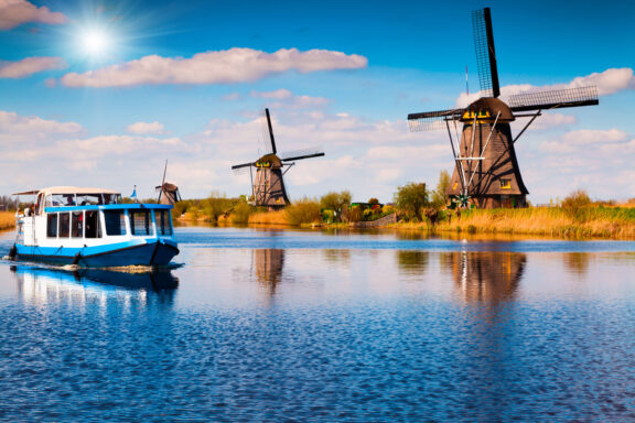 Tourist boat cruising the canal past the historic windmills of Kinderdijk, Netherlands