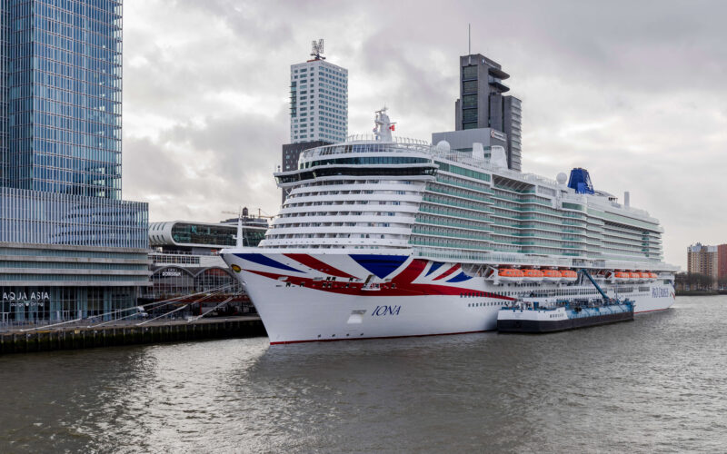P&O Cruises Iona with Union Jack bow docked at Rotterdam Cruise Terminal on Wilhelminapier, with the Rotterdam skyline in the background