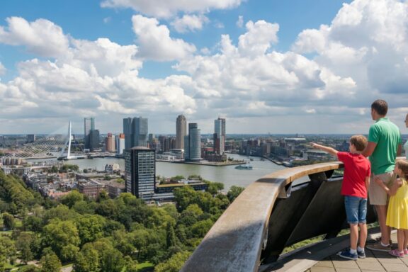 Family with two children pointing at the Rotterdam skyline and Erasmus Bridge from the Euromast observation tower
