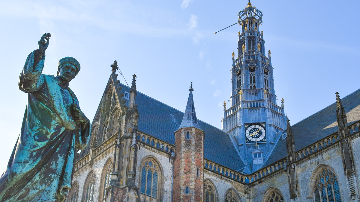 A bronze statue on the Grote Markt with the tower of St Bavo’s Church rising behind it