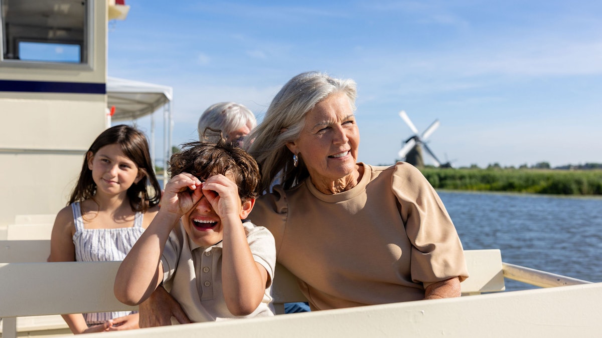Visitors on the Kinderdijk canal boat with one of the UNESCO windmills behind them