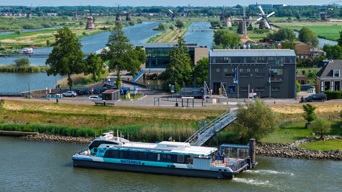 The WaterShuttle moored at its Kinderdijk jetty with the windmills and polder landscape behind