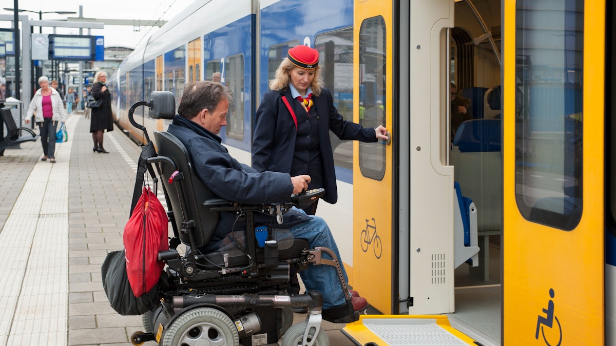A passenger boarding an NS Intercity train at the platform with staff assistance